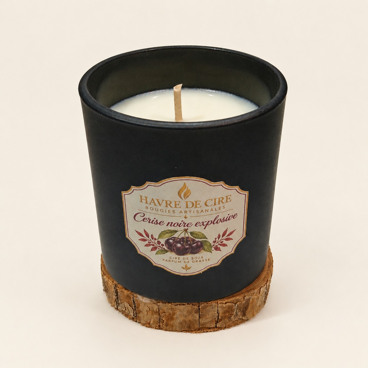Bougie Havre de Cire Cerise noire explosive en cire de soja, pot en verre noir mat posé sur un rondin de bois, sur fond crème